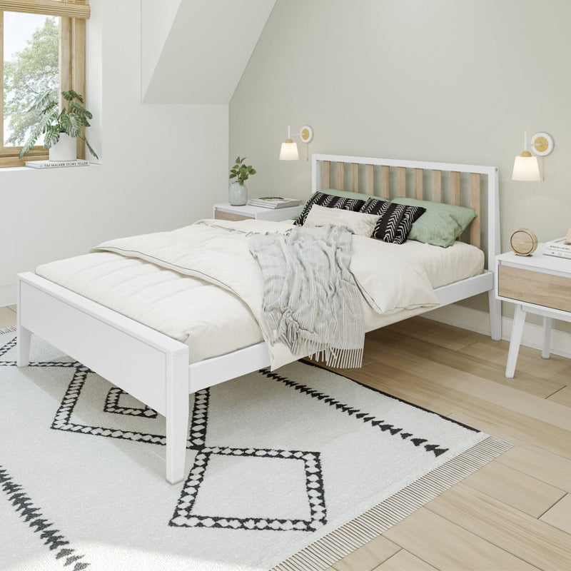 Modern minimalist Scandinavian bedroom interior with white platform bed, neutral linen bedding, green accent pillows, patterned rug, wooden floor, bedside tables, wall sconces and indoor plants
