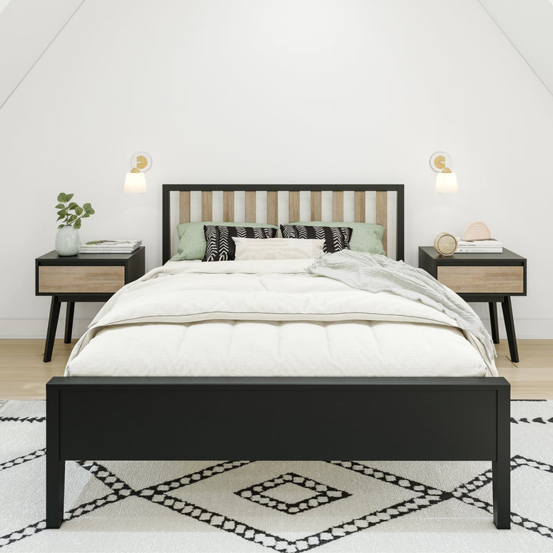 Minimalist modern bedroom interior with black-framed wooden slat bed, neutral linens, green accent pillows, patterned rug, matching nightstands and wall sconces