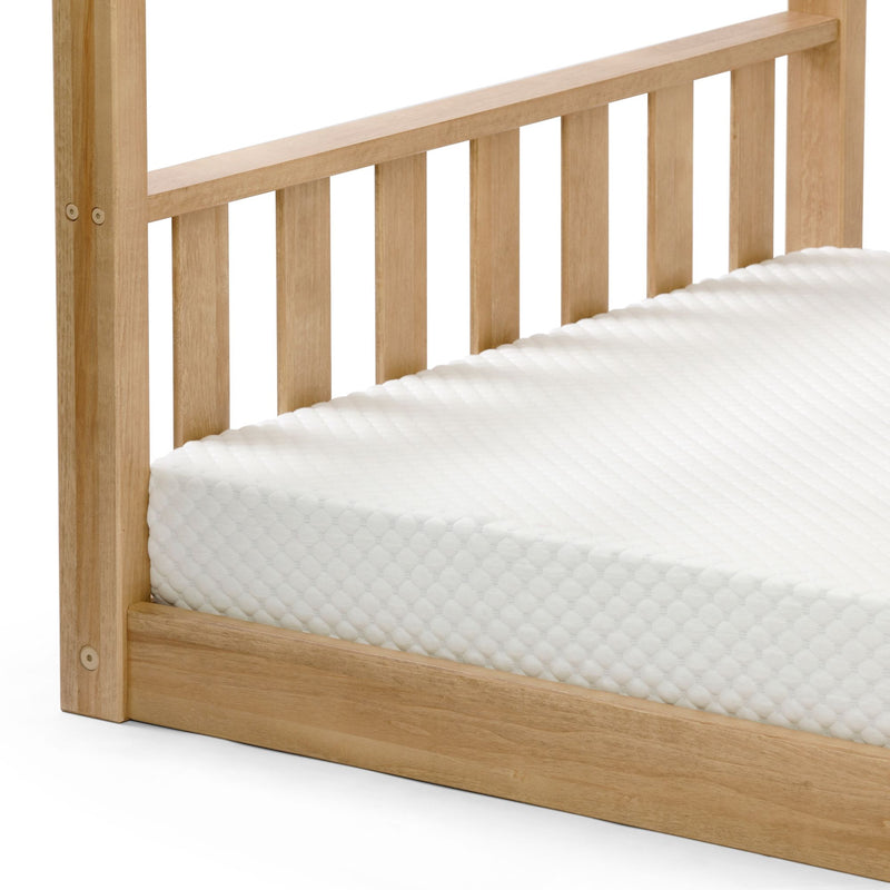 Light natural wood slatted bed frame headboard with white textured mattress corner, minimalist wooden platform bed detail