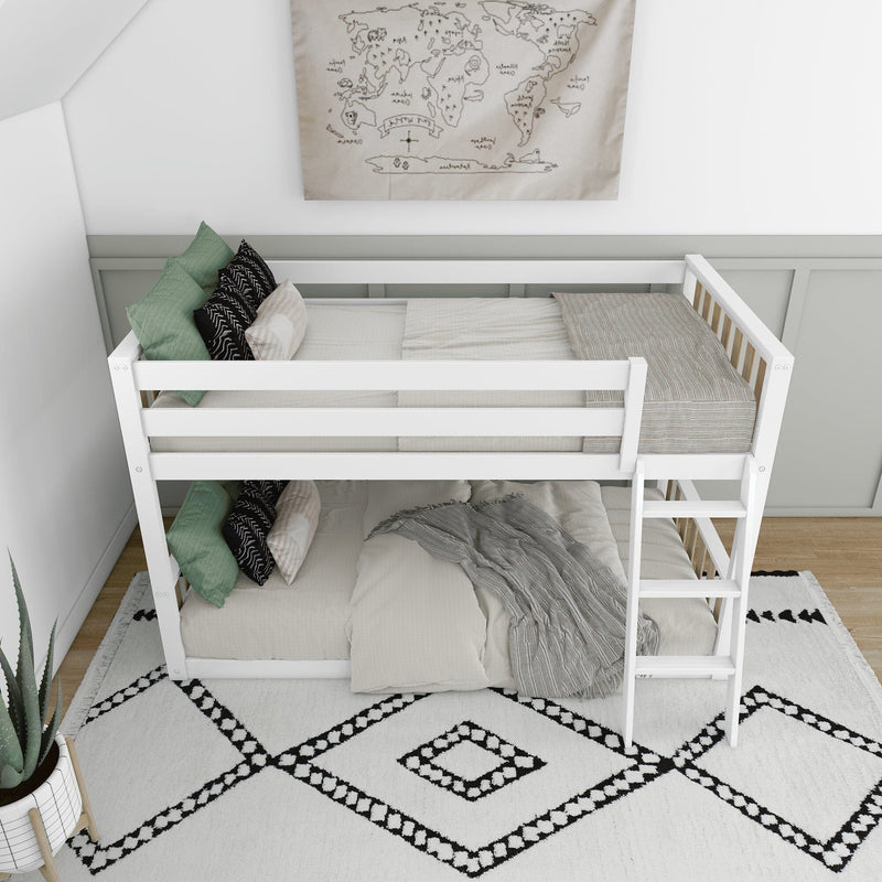 White wooden bunk bed in modern kids' bedroom with neutral bedding, green and black accent pillows, ladder, world map wall art and black-and-white geometric rug