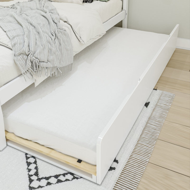 White pull-out trundle bed with mattress under a modern white bed frame, grey throw blanket and patterned rug on hardwood floor — space-saving under-bed guest or kids bed