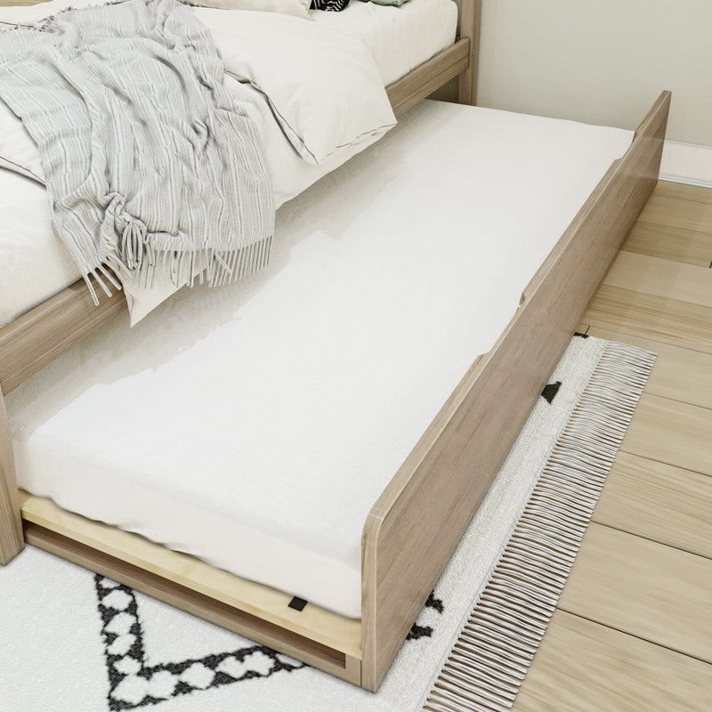 Pull-out trundle bed tucked under a light wood platform bed with white mattress, neutral throw and patterned rug — space-saving guest bed for small bedrooms