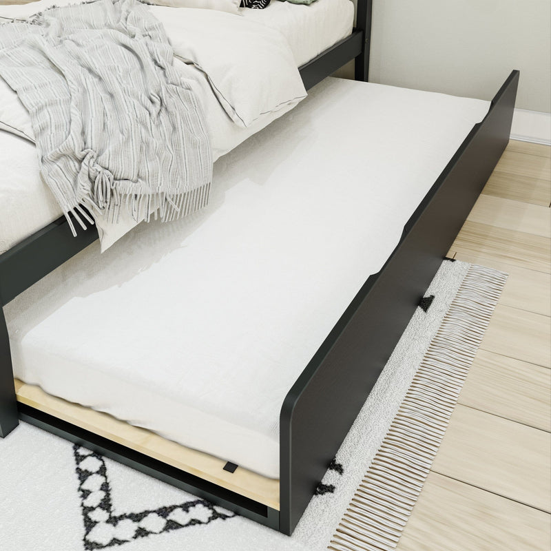 Black wooden trundle bed pulled out from under a platform bed with white mattress and throw, on light wood floor and patterned rug — space-saving guest or kids bed for small bedrooms