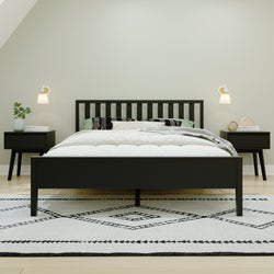 Modern bedroom with a black wooden bed frame, white bedding, and matching nightstands in a minimalist design.