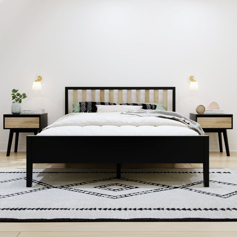Modern minimalist bedroom with black-framed wooden slat bed, white bedding, patterned pillows, nightstands with lamps and geometric rug