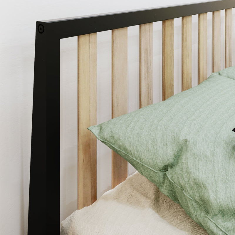 Modern black metal frame bed headboard with vertical light wood slats and green linen pillow on beige bedding