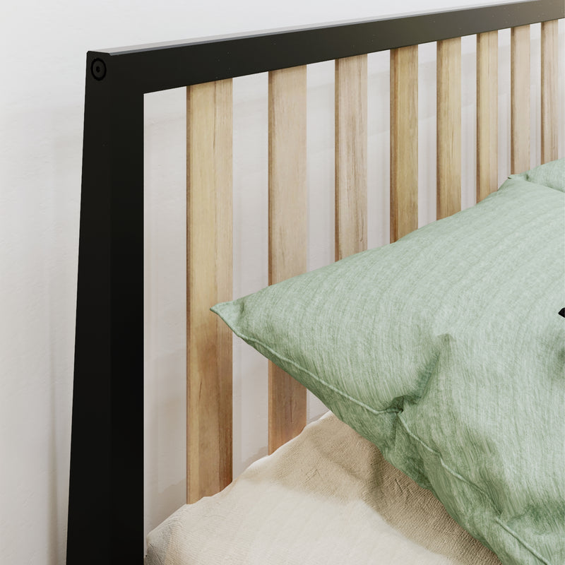 Modern black metal frame and natural wood slat headboard with sage green linen pillow and beige bedding in a minimalist bedroom setting