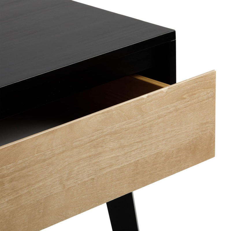 Close-up of modern nightstand with matte black top, partially open natural oak drawer and black metal leg
