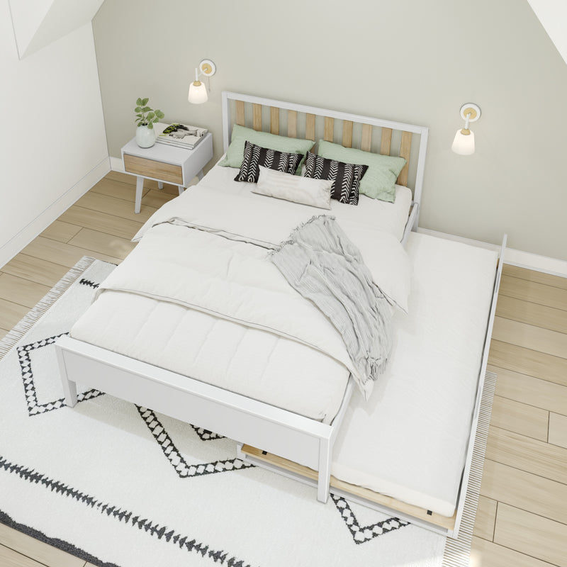 Minimalist Scandinavian bedroom with white platform bed and pull-out trundle, light wood floors, patterned rug, bedside table with plant, green accent pillows and wall sconces