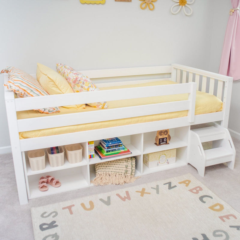 White wooden kids loft bed with built-in storage, yellow bedding, floral pillows and alphabet rug in pastel nursery