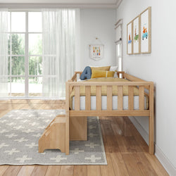 Wooden toddler bed with safety rails and stairs in a bright, modern kids' room with large windows.