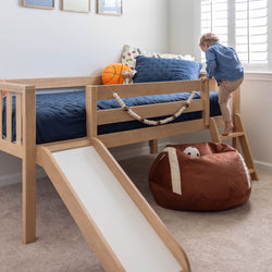 Child climbing wooden loft bed with slide and beanbag in cozy bedroom.