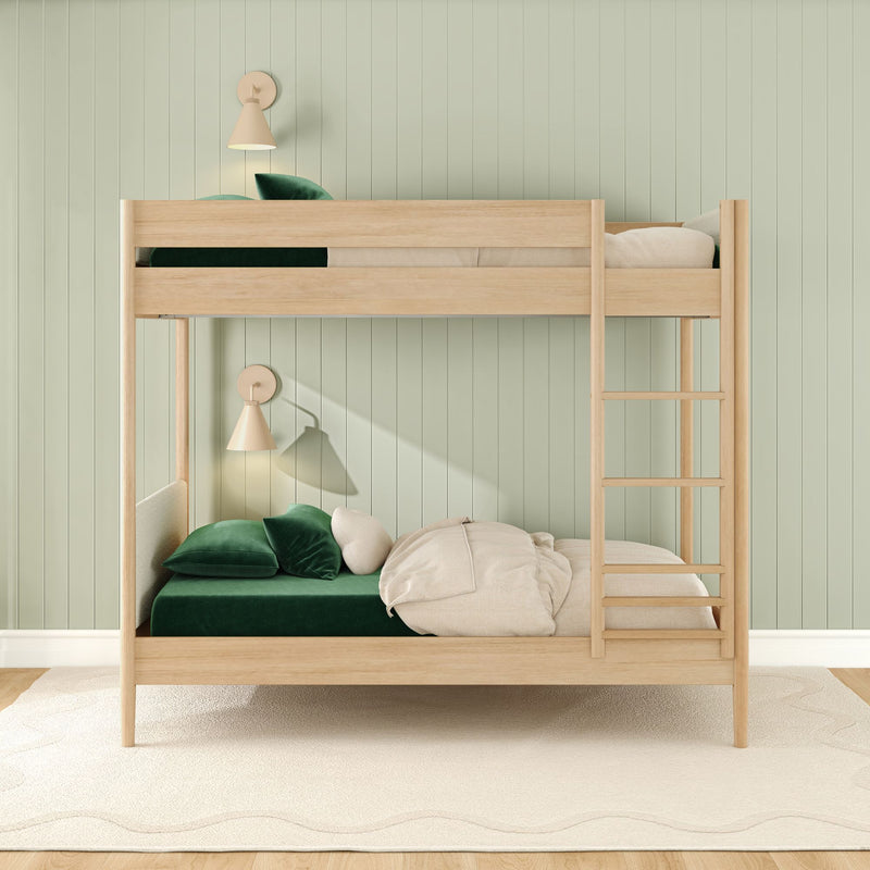 Modern wooden twin-over-twin bunk bed in kids' bedroom with emerald green velvet bedding, cream pillows, ladder, wall sconces and mint green paneled wall