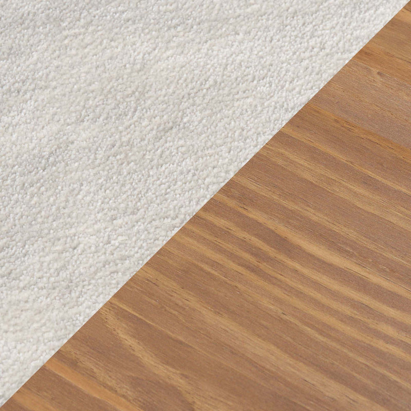 Close-up of white plush carpet meeting oak hardwood floor at a diagonal flooring transition, showing carpet texture and wood grain for home flooring choices