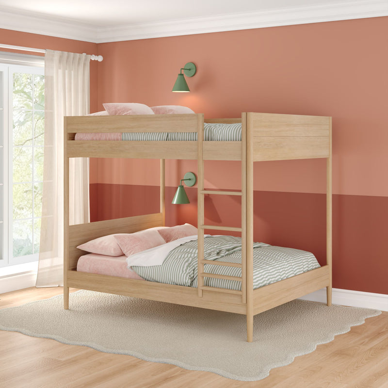 Twin-over-full natural wood bunk bed in modern children's bedroom with pink pillows, striped bedding, green wall sconces, ladder, and coral two-tone wall