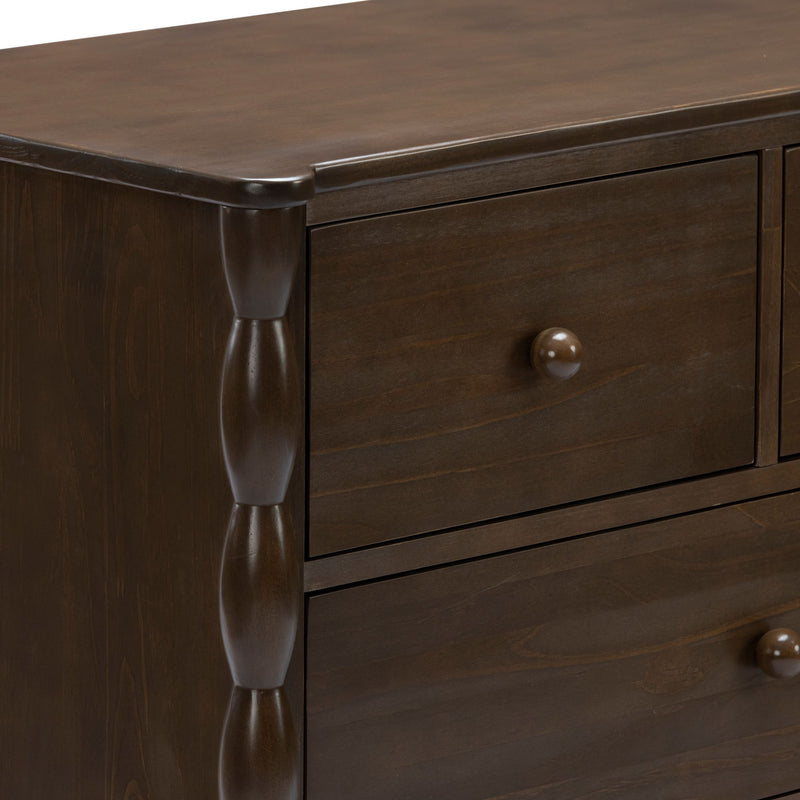Close-up of dark brown solid wood dresser corner with turned leg, round drawer knob and smooth wood grain finish