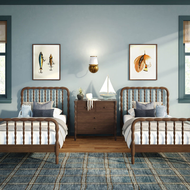 Coastal kids' bedroom with twin wooden spindle beds, light blue walls, sailboat decor, plush octopus, framed fish prints and navy plaid rug