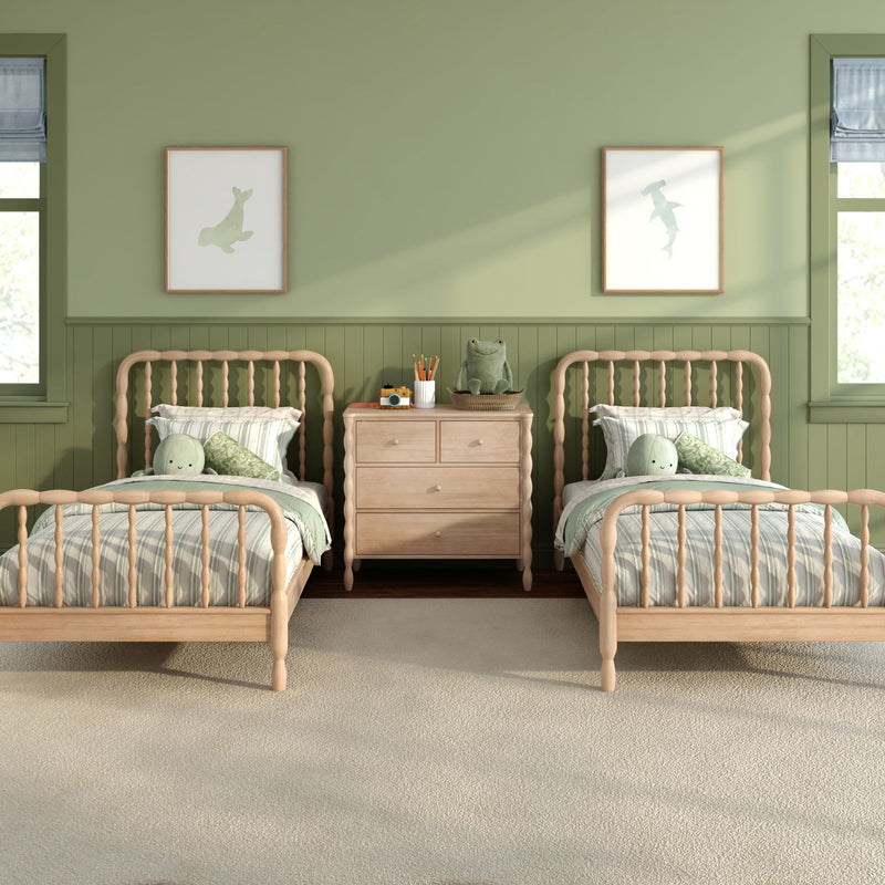Kids' bedroom with twin wooden spindle beds, green painted walls, natural wood nightstand, plush frog toy and coastal fish wall art