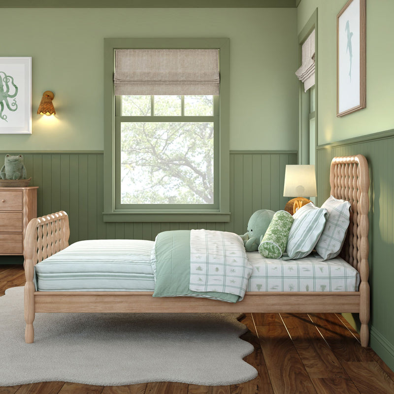 Cozy green children's bedroom with natural wood bed, mint bedding and pillows, plush frog toy, roman shade window, rattan lamp and sea-themed wall art