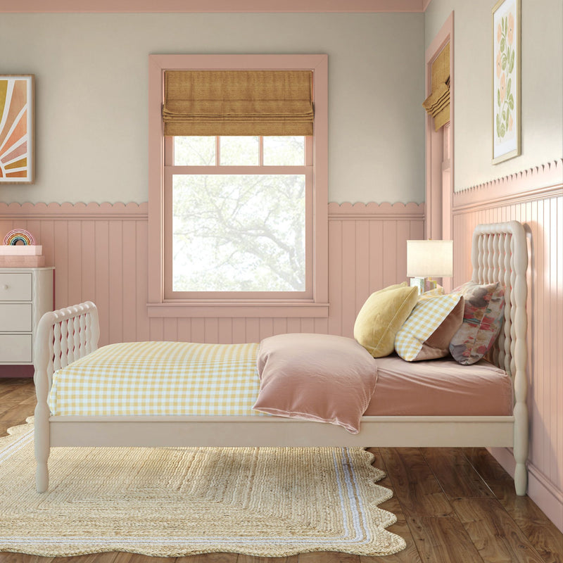Pastel pink girl's bedroom with tufted headboard, yellow gingham bedding, mustard Roman shade, scalloped wainscoting and jute rug
