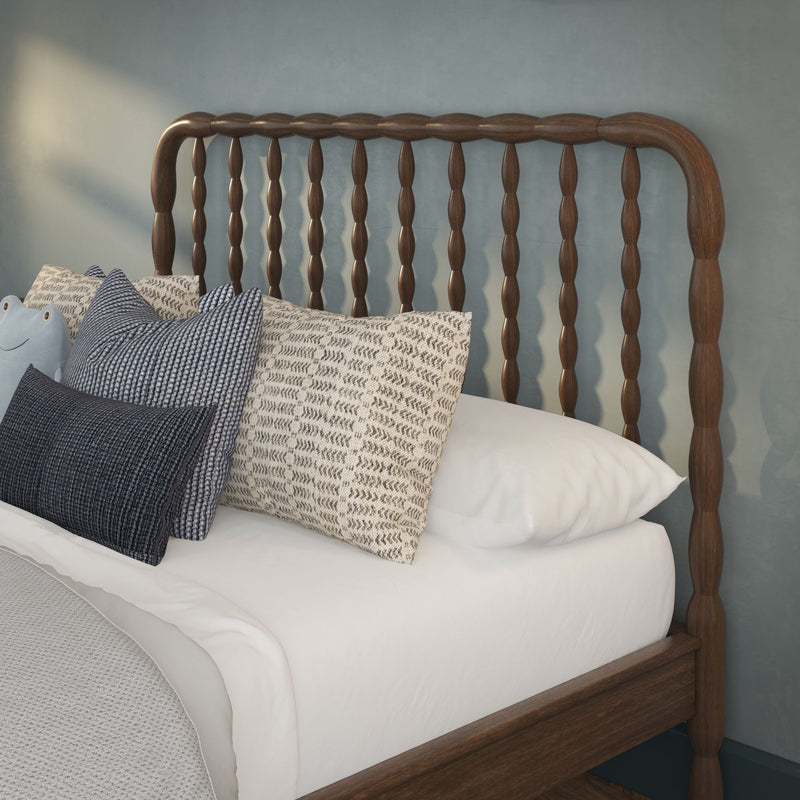 Dark wooden spindle headboard with layered neutral and blue patterned pillows on white bedding against a blue accent wall