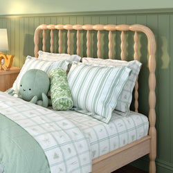 Pale wood spindle headboard bed with green striped pillows, sea‑themed plaid bedding and octopus plush in a cozy kids' bedroom with green wainscoting
