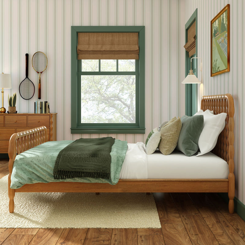 Cozy bedroom with wooden bed frame, green bedding and trim, striped wallpaper, wooden dresser and vintage tennis rackets