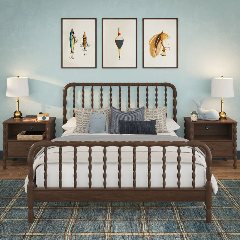 Coastal kids bedroom with dark wooden spindle bed, navy plaid rug, three framed nautical prints, matching nightstands and lamps