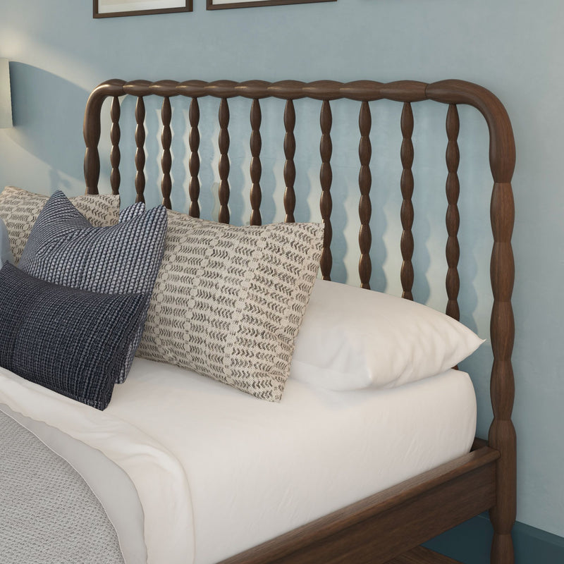 Wooden spindle headboard with white bedding and textured navy and beige decorative pillows in a light-blue bedroom