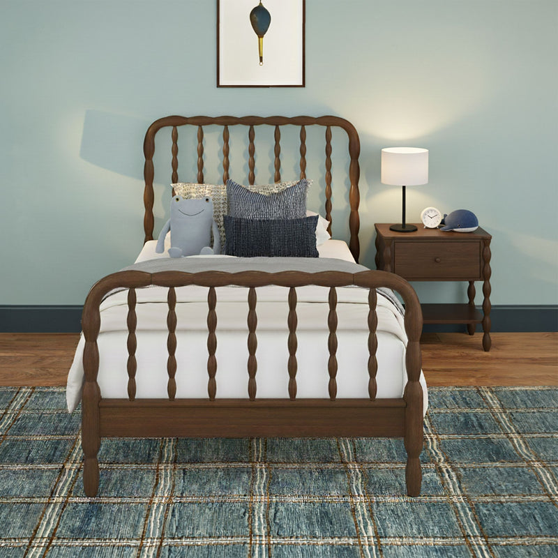 Kids bedroom with wooden spindle twin bed, blue accent wall, plush frog toy and layered navy pillows, wooden nightstand with white table lamp and alarm clock, textured blue patterned area rug