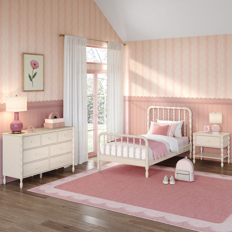 Pink girls' bedroom nursery with scalloped wainscoting, white spindle bed, dresser, sheer curtains, floral wall art and pink rug