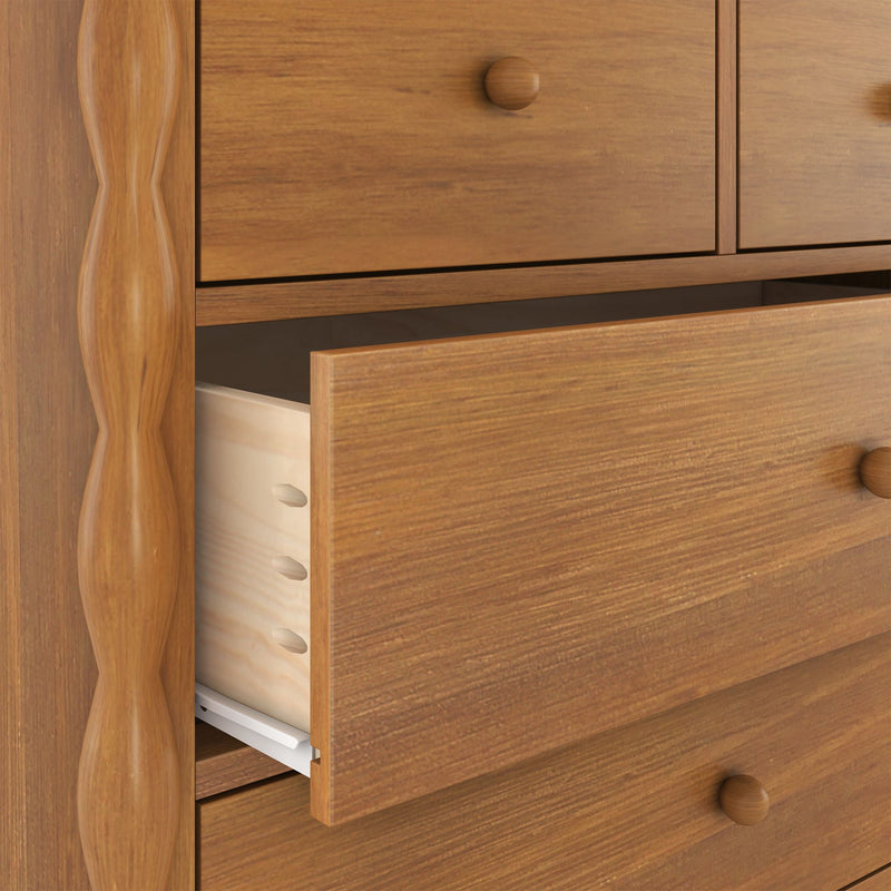 Close-up wooden dresser with partially open drawers, dovetail joints, round knobs and warm wood-grain finish for bedroom storage