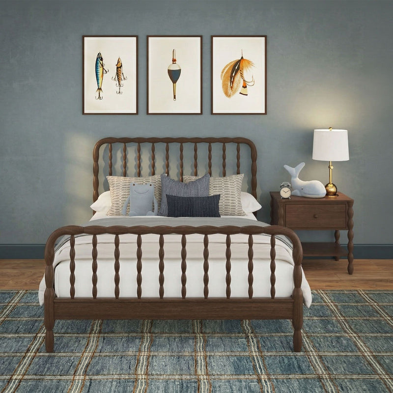Coastal farmhouse bedroom with wooden spindle bed, navy accent wall, nautical framed art, blue plaid rug, rustic nightstand, brass table lamp and plush whale decor.