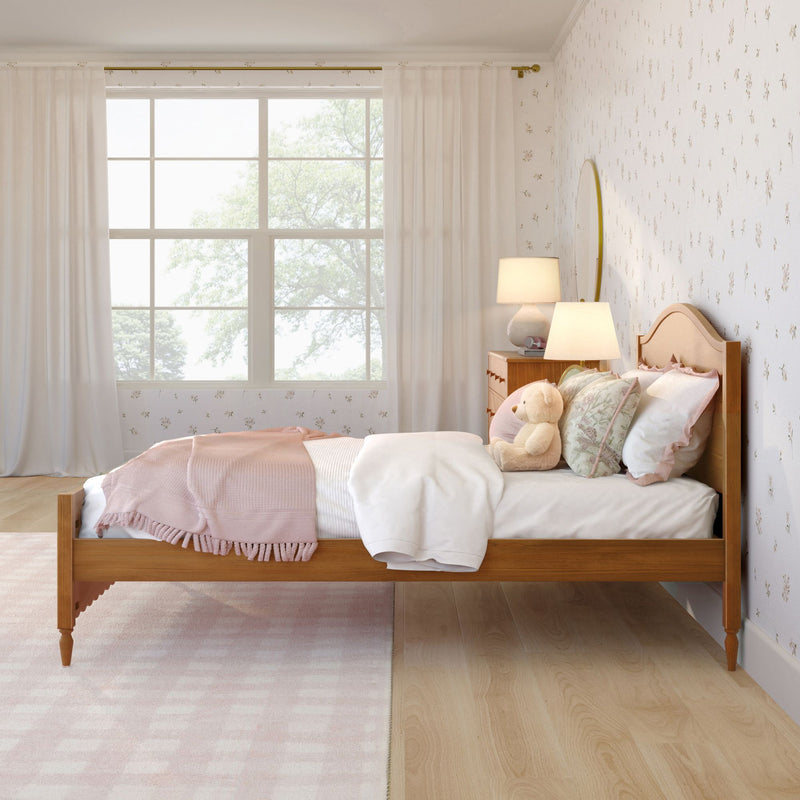 Cozy pastel pink kids' bedroom with wooden bed, teddy bear, floral wallpaper, bedside lamp and large window with sheer curtains