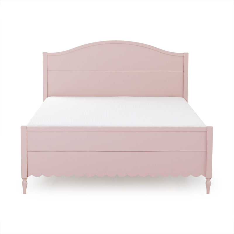 Pastel pink wooden twin bed with arched headboard and scalloped footboard, children's bedroom furniture