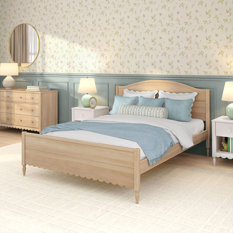 Cozy coastal farmhouse bedroom with light wood bed, blue pillows and throw, floral wallpaper, mint wainscoting, nightstands, lamps and round mirror