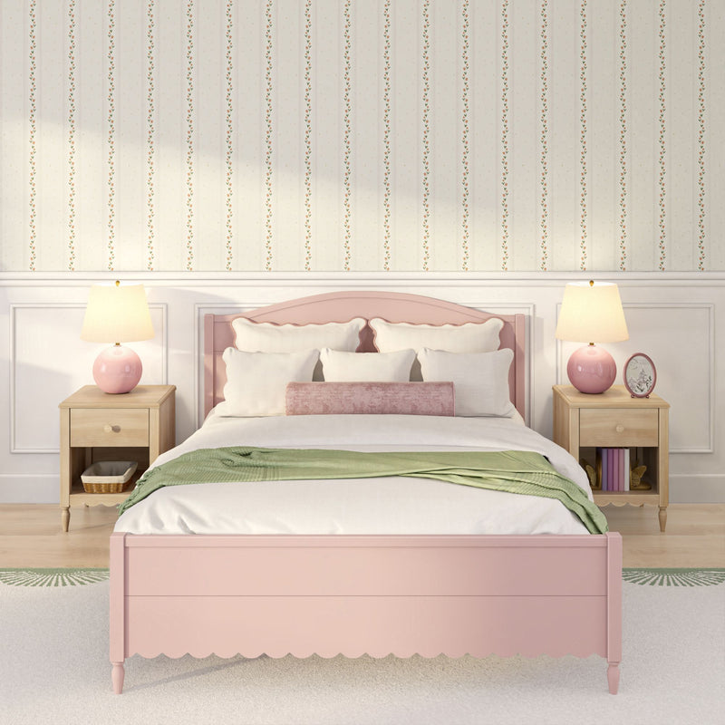 Pastel pink bedroom with scalloped pink bed frame, white bedding and pillows, green throw blanket, floral striped wallpaper, wooden nightstands and pink table lamps
