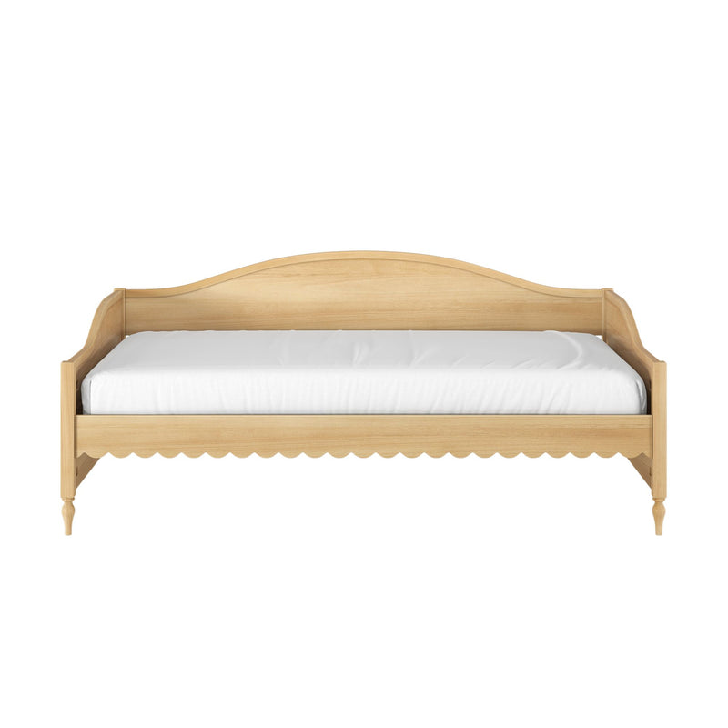 Light natural wood daybed with curved headboard, scalloped apron and turned legs, white mattress, farmhouse/Scandinavian style