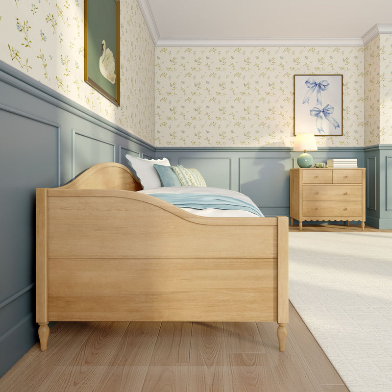 Cozy children's bedroom with light wood bed and dresser, pastel blue wainscoting, floral wallpaper, soft bedding and bedside lamp