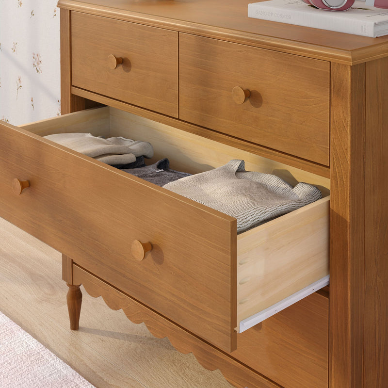 Solid oak dresser with open drawer showing folded sweaters, bedroom storage chest of drawers with round wooden knobs