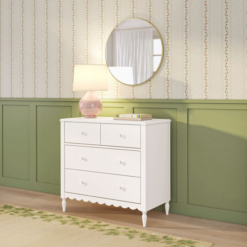 White chest of drawers with pink ceramic table lamp and round gold mirror over green wainscoting and vintage floral striped wallpaper, cozy bedroom decor