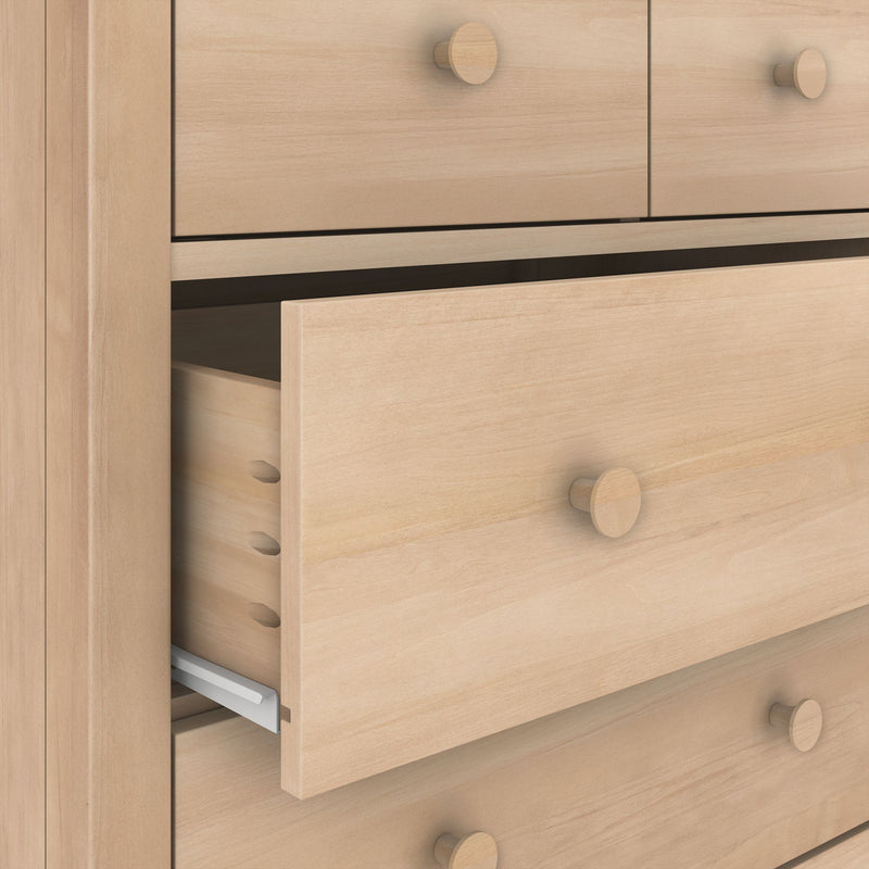 Close-up of light maple dresser with round wooden knobs and a partially open drawer revealing dovetail joints and metal drawer slide