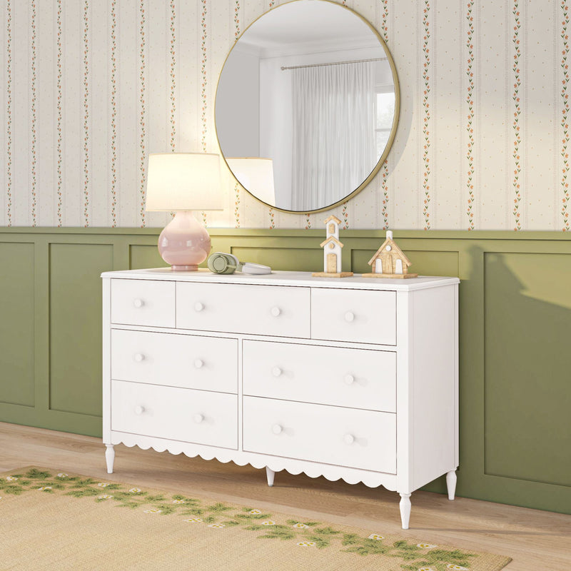 White scalloped dresser with round gold mirror, pink table lamp and green paneled wainscoting against floral striped wallpaper