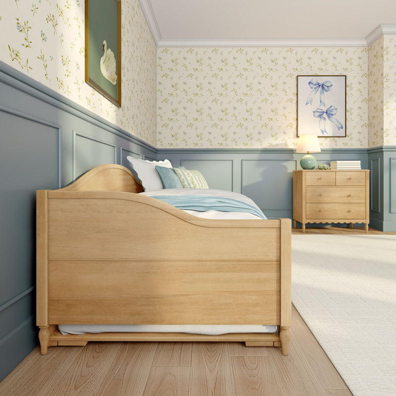 Cozy kids bedroom with light wood bed, pale blue wainscoting, floral wallpaper, wooden dresser and bedside lamp in soft pastel decor