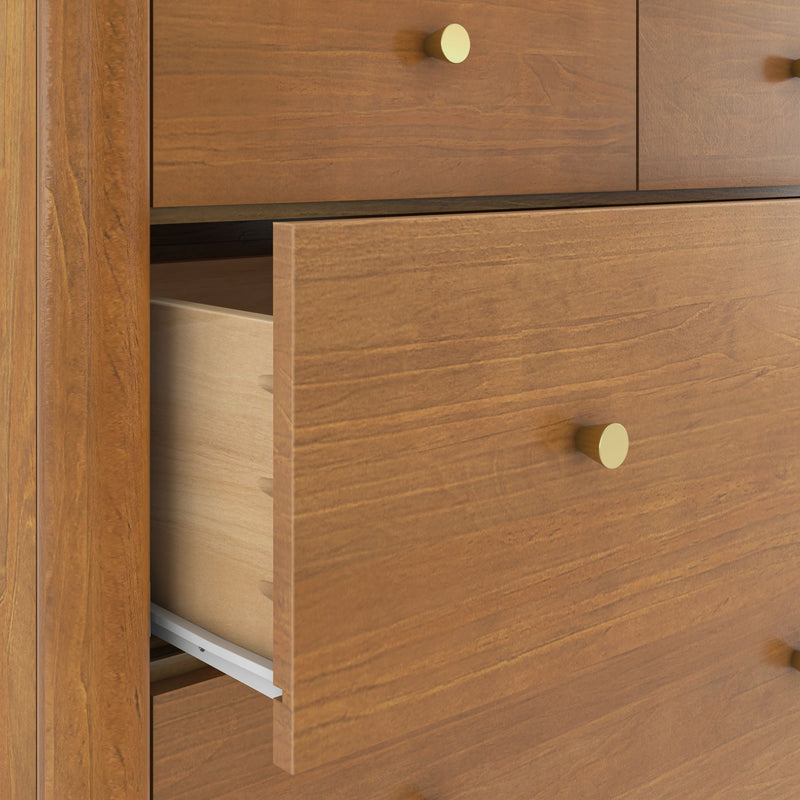 Close-up of a solid wood bedroom dresser with a partially open drawer, brass knob, and visible wood grain.