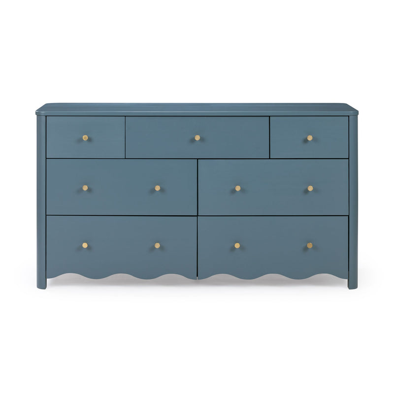 Matte blue painted wooden dresser with brass knobs and scalloped skirt, multi-drawer bedroom storage chest in coastal-modern style