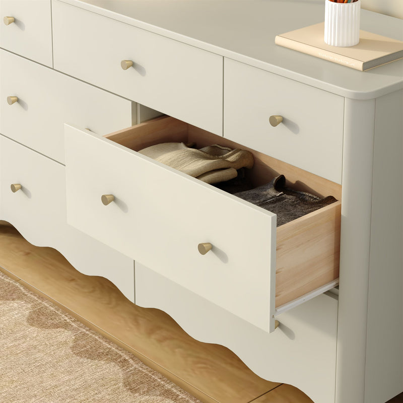 Cream white bedroom dresser with open drawer revealing folded clothes, brass knobs and natural wood interior for bedroom storage