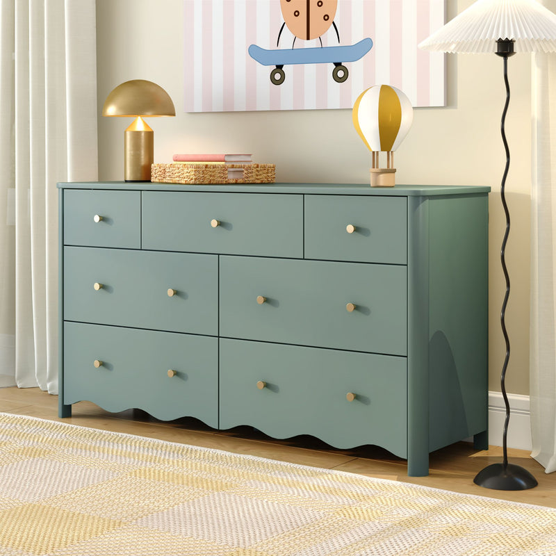 Teal wooden nursery dresser with gold knobs and scalloped base, styled with a lamp and hot-air balloon decor