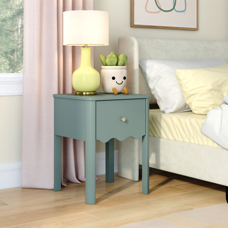 Teal wooden nightstand with scalloped drawer, yellow ceramic lamp, smiling succulent planter, and cozy beige upholstered bed in pastel bedroom décor