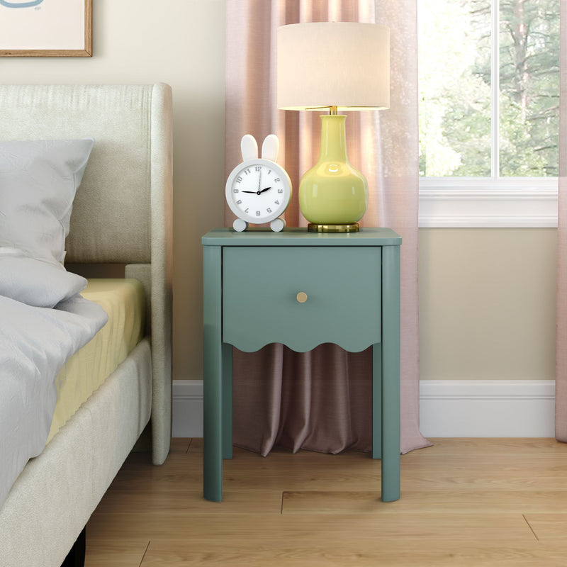 Teal bedside nightstand with scalloped drawer, yellow ceramic lamp and bunny alarm clock next to upholstered bed in cozy modern bedroom with pink curtains and natural light